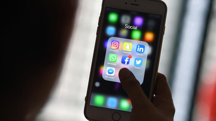 This photo illustration taken on March 22, 2018 shows a woman looking at Social Networking applications Facebook, Instagram, Snapchat, Whatsapp, Twitter, Messenger and Linkedin on a smartphone in Kual