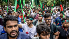 Protesters hold Bangladeshi national flags as they march to block the house of Sheikh Mujibur Rahman in Dhaka on August 15, 2024.