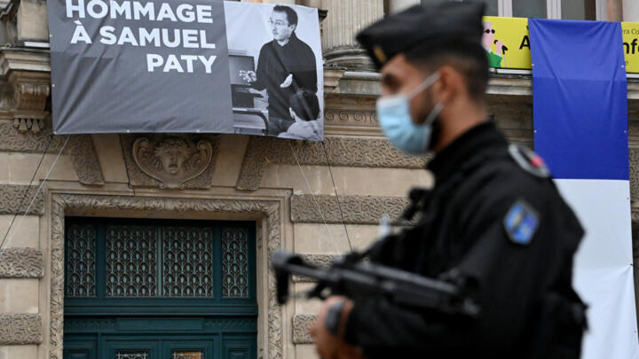 A police officer stands next to a portrait of Samuel Paty on display at the Opéra Comédie in Montpellier, southern France, on October 21, 2020.