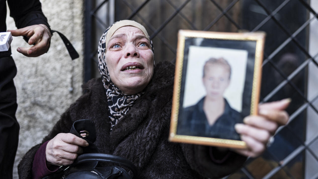 A Syrian woman, who lost two of her children, reacts as she couldn't find the body of her third child (portrait), who was detained in 2012, outside the morgue of Damascus hospital.