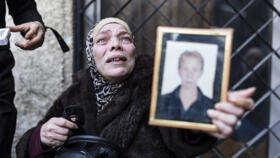 A Syrian woman, who lost two of her children, reacts as she couldn't find the body of her third child (portrait), who was detained in 2012, outside the morgue of Damascus hospital. 