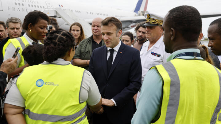 France's President Emmanuel Macron (C) speaks with staff members as he arrives on the tarmac of Dzaoudzi's airport, on the French Indian Ocean territory of Mayotte, on December 19, 2024.