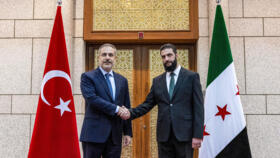 This handout picture shows Turkey's Foreign Minister Hakan Fidan (L) being received by Hayat Tahrir al-Sham (HTS) leader Ahmed al-Sharaa in Damascus on December 22, 2024.