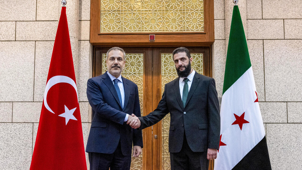 This handout picture shows Turkey's Foreign Minister Hakan Fidan (L) being received by Hayat Tahrir al-Sham (HTS) leader Ahmed al-Sharaa in Damascus on December 22, 2024.
