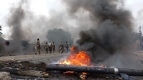 Pedestrians walk past a burning barricade in Maputo, Mozambique on December 24, 2024.