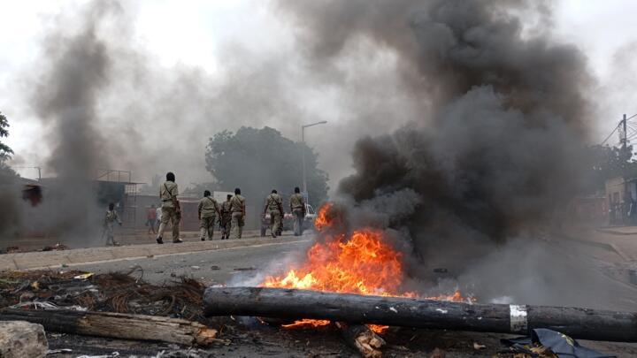 Pedestrians walk past a burning barricade in Maputo, Mozambique on December 24, 2024.