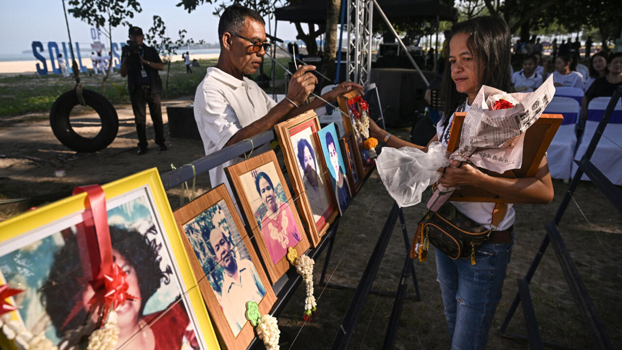 A woman places portraits of her relatives at the Ban Nam Khem Tsunami Memorial Park in southern Thai province of Phang Nga on December 26, 2024.