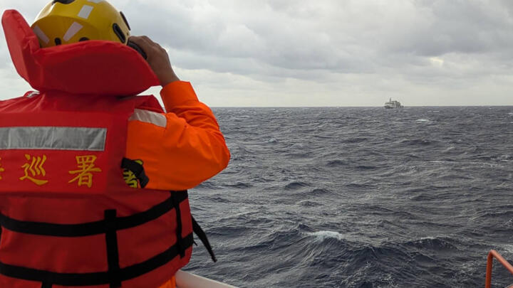 A member of the Taiwan Coast Guard monitors a Chinese vessel in waters east of Taiwan as China holds its biggest maritime drills in years