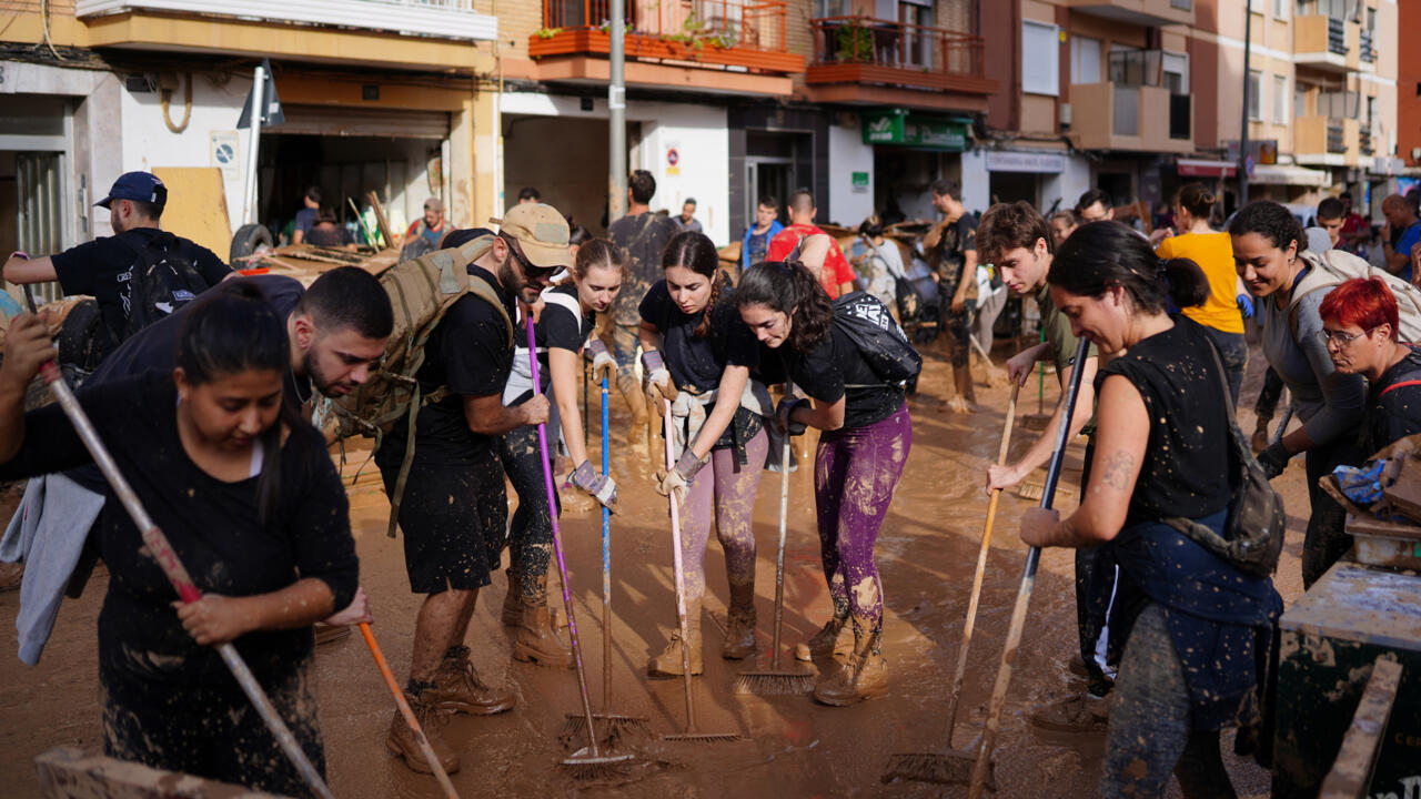 Voluntarios y vecinos limpian el barro de las calles de la localidad de Paiporta el 1 de noviembre de 2024, tras las devastadoras inundaciones que azotaron la región de Valencia, en el este de España