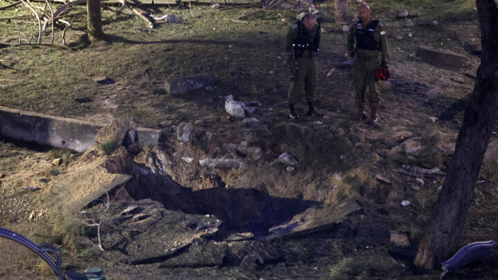 Israeli emergency responders inspect a crater at the site where a projectile fired from Yemen landed in Tel Aviv on December 21, 2024.