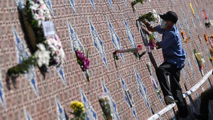 Un homme dépose des fleurs devant le Mur-mémorial du tsunami à Ban Nam Khem, en Thaïlande, le 26 décembre 2024.