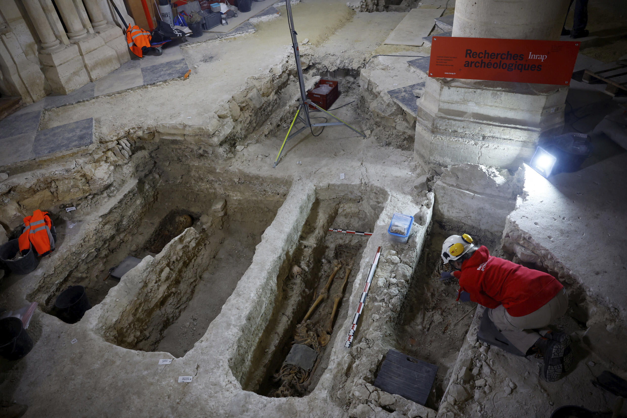 An archaeologist examines a skeleton in a grave at the burial site discovered in the nave of Notre-Dame on December 8, 2023.