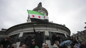 A Syrian living in France waves the opposition's flag during a rally on Republique square after the Syrian government fell in a stunning end to the 50-year rule of the Assad family, De