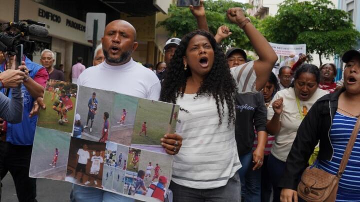 Luis Arroyo, a la izquierda, lleva fotografías de sus dos hijos desaparecidos, Ismael y Josué, quienes fueron vistos por última vez el 8 de diciembre huyendo de un convoy militar con otros dos jóvenes, mientras protesta con su familia y activistas afuera de la fiscalía en Guayaquil, el lunes 23 de diciembre de 2024.