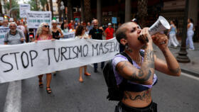 A demonstrator uses a megaphone as people protest against mass tourism, in Alicante, Spain, July 13, 2024. 