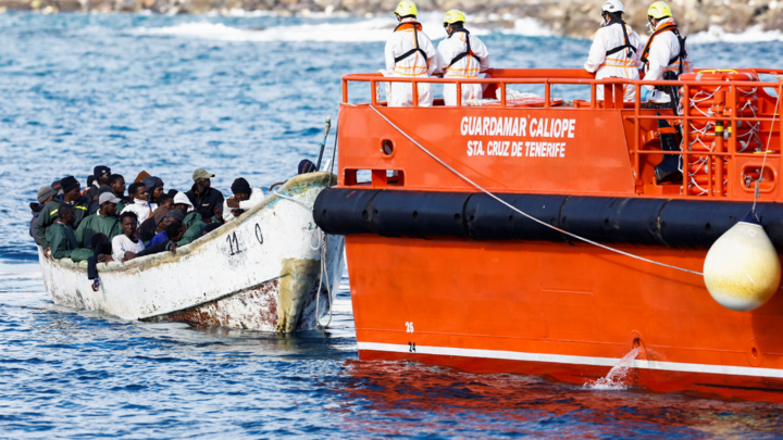 Un rescatista ayuda a un niño migrante a desembarcar de un barco de la Guardia Costera española en el puerto de Arguineguín, en la isla de Gran Canaria.